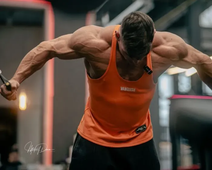 Lester Buhrmann beim Kabelzug-Training im Gym, im orangefarbenen Tanktop