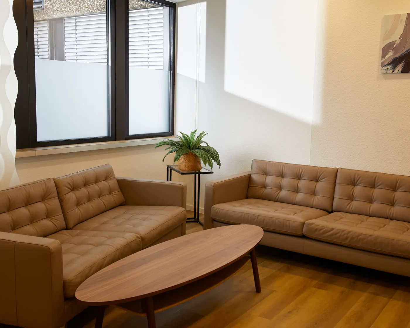 Wartebereich der Klinik in Mülheim mit zwei Ledersofas, Couchtisch und Pflanze